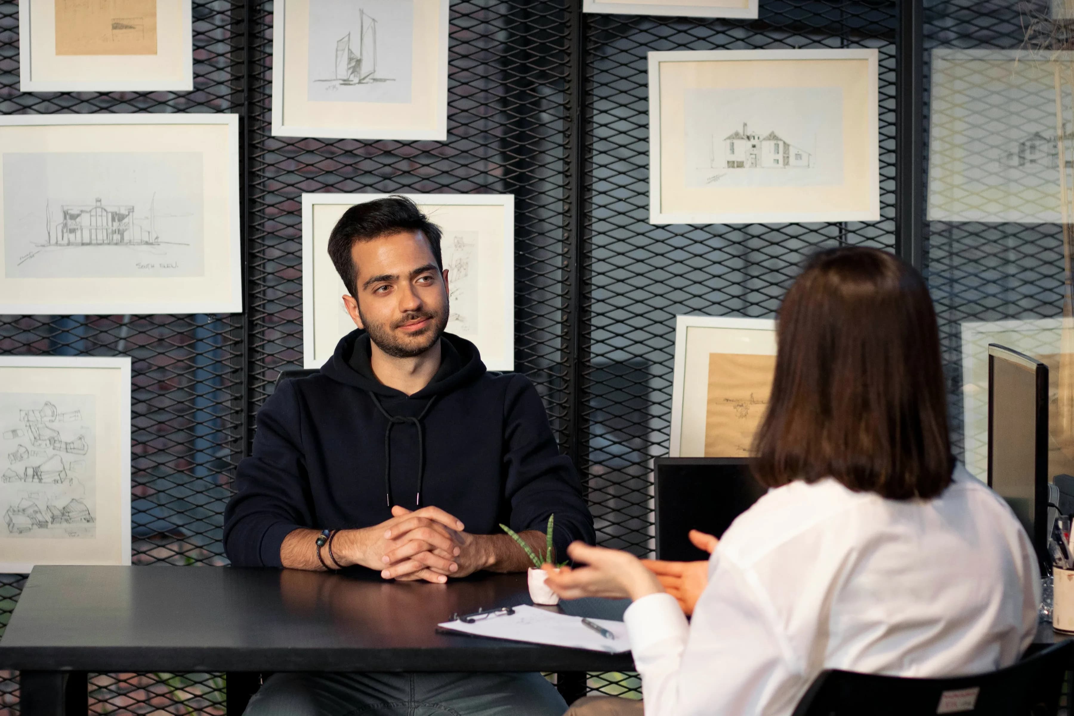 Two people talking across a table, one answering a question